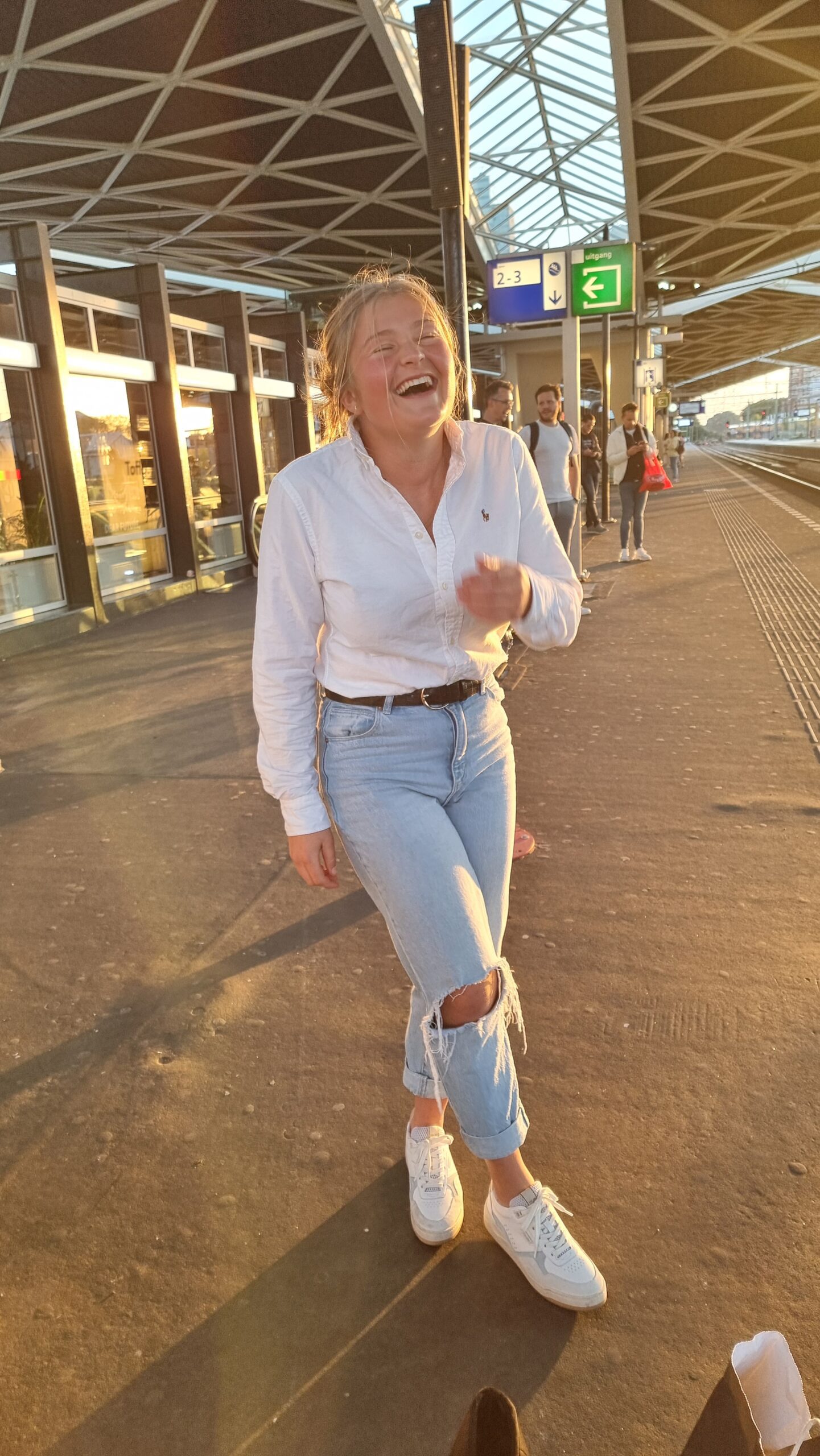 Keira laughing in the late afternoon sunshine at a railway station in the Netherlands